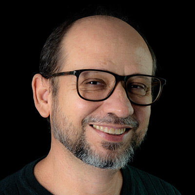 Portrait of a bearded man wearing eyeglasses against a black bac